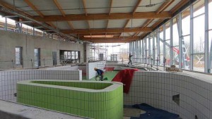 In the foreground, the pool features a lazy river, a massage bench, ends with a water park beach. On the right, the windows open onto a beach and a solarium for sunbathing.