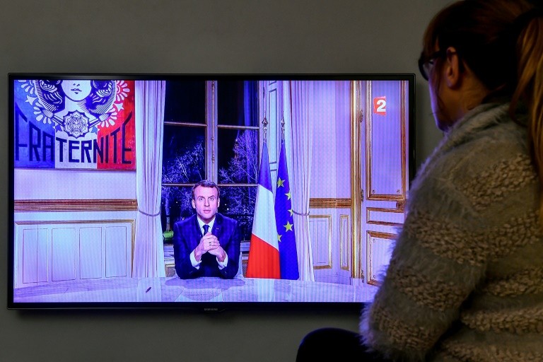 A viewer looks at Emmanuel Macron presidential wishes for the new year 2018, December 31, 2017 in Paris.