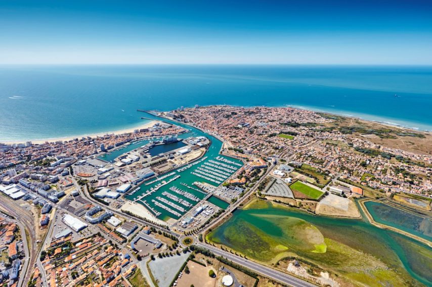 Aerial view of Les Sables-d'Olonne, with the large beach on the left, La Chaume on the right behind the channel, the marina in the middle and the beginning of the marsh, in the foreground on the right