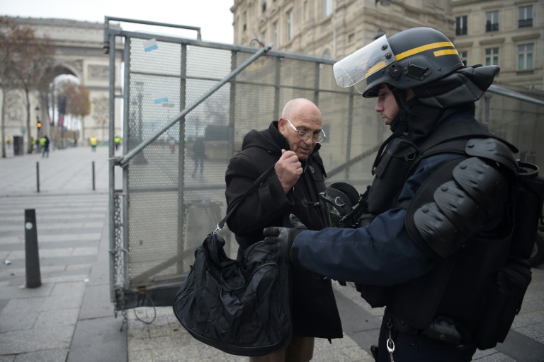 A policeman inspects the bag of a passerby on December 1, 2018 on the Champs-Elysees, Paris. 