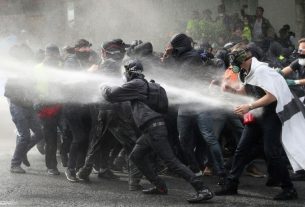 Protesters in black and hooded watered by water cannons during clashes with the police on May 1st, 2019 in Paris.