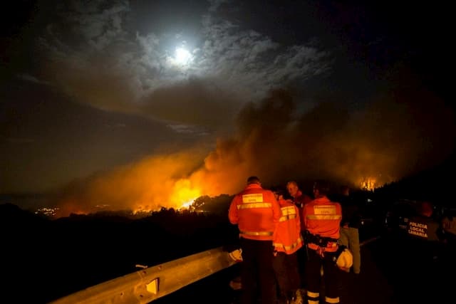 Firefighters and police watch from the road the peaks of Valleseco in flame, the last fire on the Spanish island of Gran Canaria, August 17, 2019.