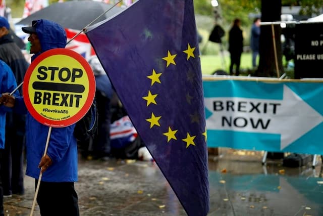 An anti-Brexit protester carries a sign and a European flag in front of the British Parliament in London on October 17, 2019. 