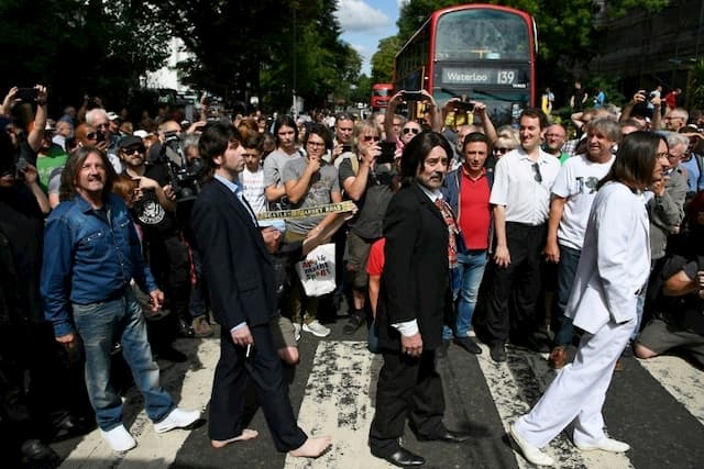 Look-alikes cross the pedestrian crossing of Abbey Road, made famous by the Beatles 50 years earlier, on August 8, 2019 in London.