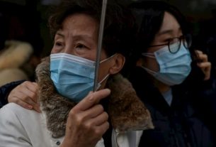 Passers-by wearing protective masks in front of a hospital in Shanghai, January 22, 2020.