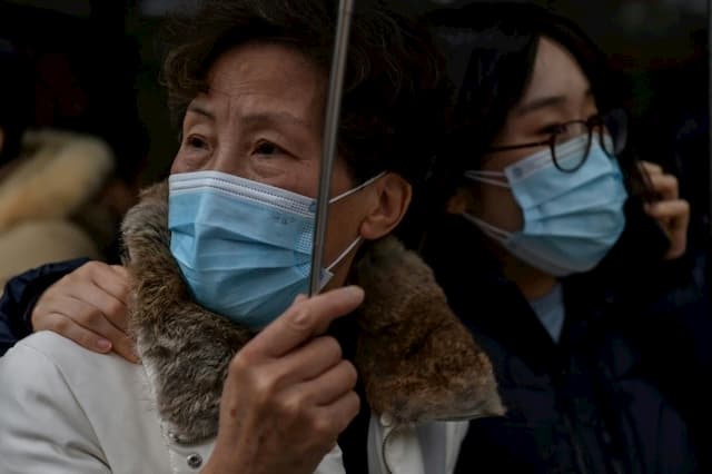 Passers-by wearing protective masks in front of a hospital in Shanghai, January 22, 2020.