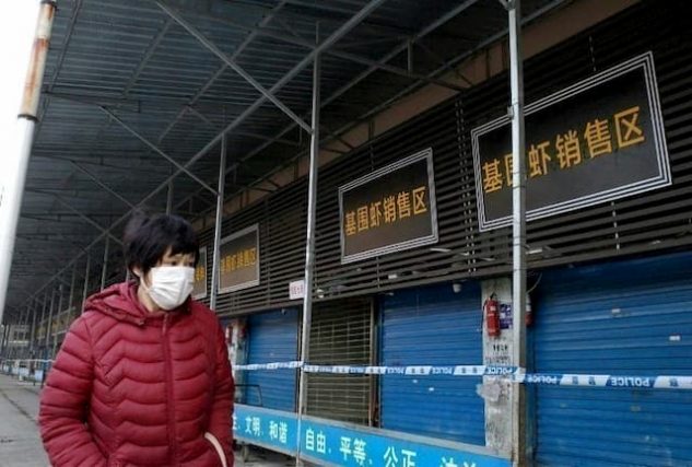 A woman walks past a closed Wuhan market after the appearance of a mysterious virus on January 12, 2020 in China. 