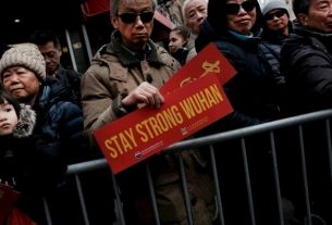 A man displays a "Stay Strong Wuhan" message in solidarity with the hometown of the new coronavirus epidemic in China during a ceremony celebrating the Lunar New Year on February 9, 2020 in New York.