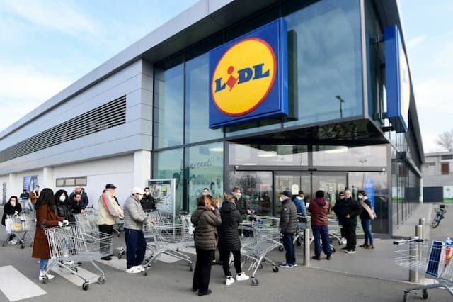 People wearing protective masks wait outside the entrance to a Lidl supermarket on February 23, 2020 in Casalpusterlengo, Italy.