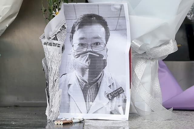 A photo of doctor Li Wenliang, in front of which a bouquet of flowers was placed, in front of a wing of the hospital in Wuhan, China, on February 7, 2020.