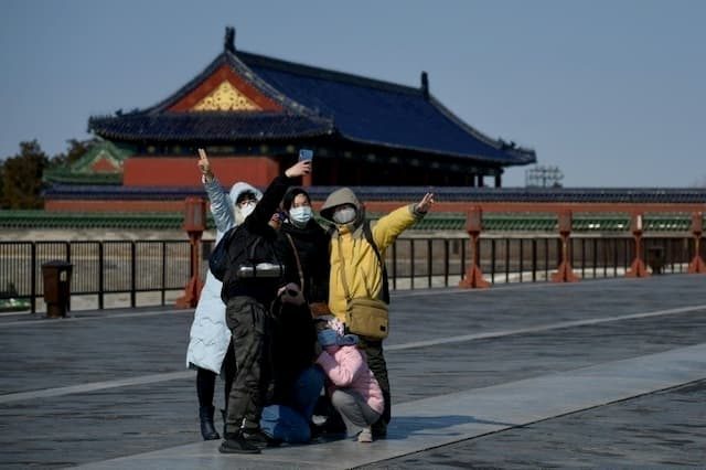 Tourists take selfies in a park in Beijing, February 15, 2020. 