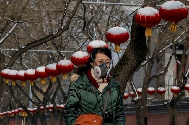 A woman with a face covered with a protective mask walks on a street in Beijing after a snowfall, on February 2, 2020. 