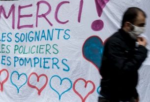Paris, March 21, 2020. A man walks past a banner thanking professions mobilized on the ground in the midst of a coronavirus pandemic