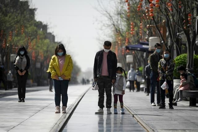 Passers-by meditate during the national tribute for the dead of the Covid-19, on April 4, 2020 in Beijing.