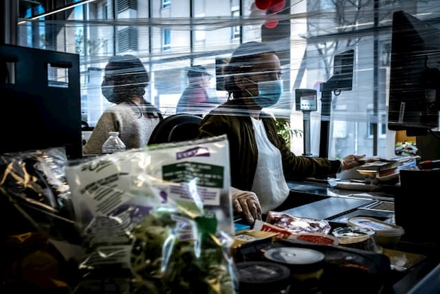 Cashiers wear gloves and a protective mask against coronavirus in a supermarket in Givors, on April 15, 2020 near Lyon.