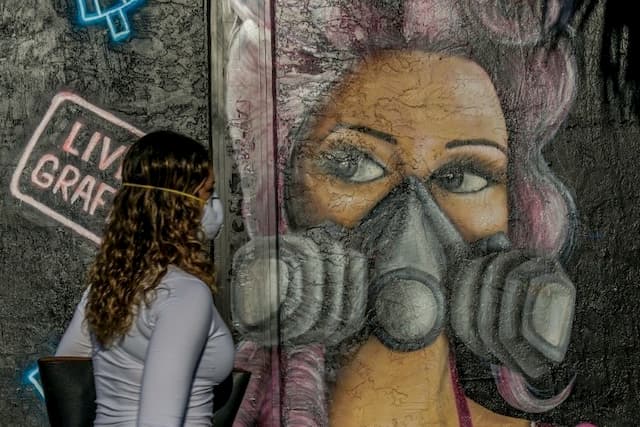 A woman walks past a mural in a neighborhood of Miami, April 3, 2020